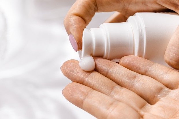 a woman putting lotion on her hands