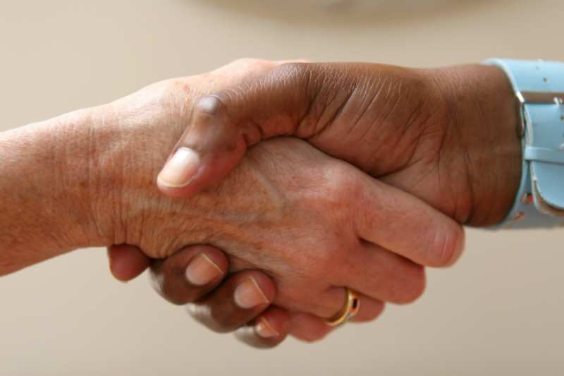 A doctor’s hand is shaking the hand of a patient.