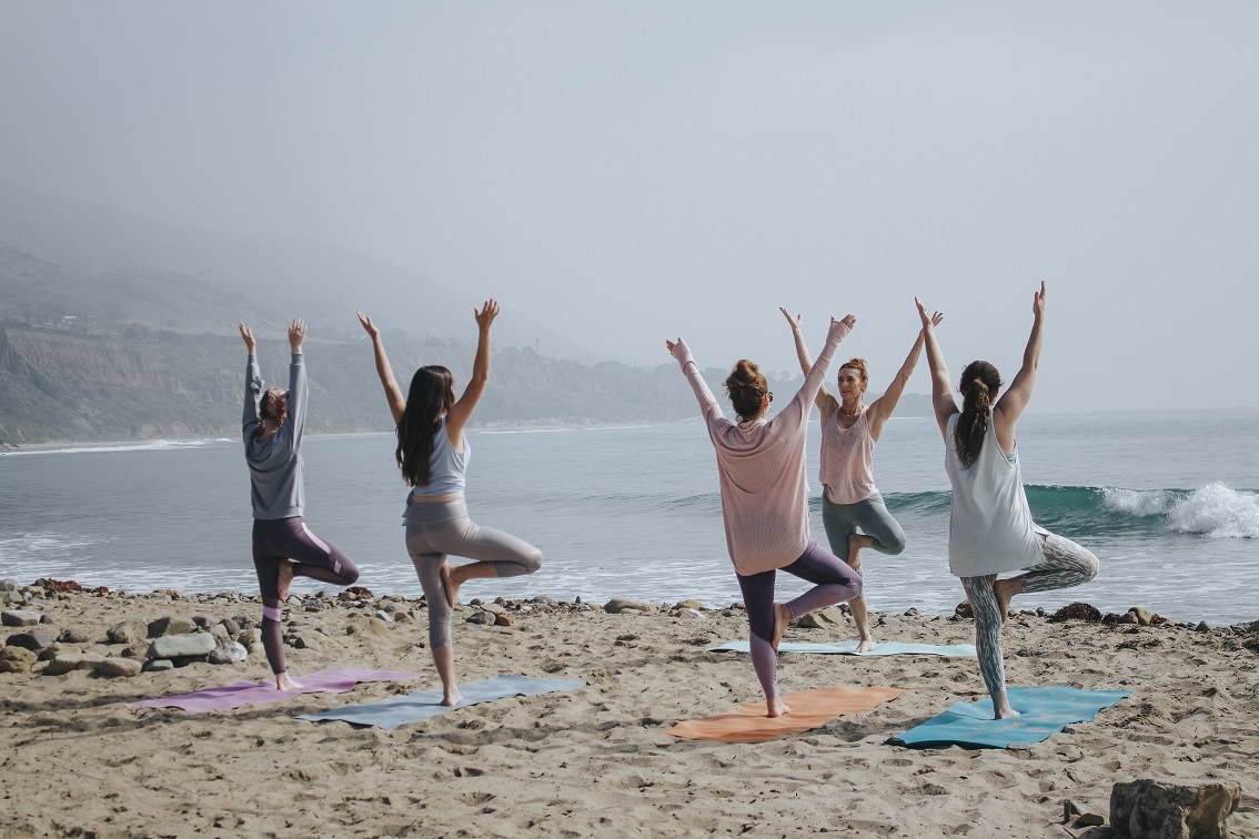 Group of students in tree pose on a beach