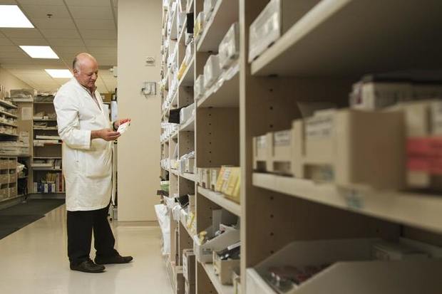 Male pharmacist in white coat studying medicine packages