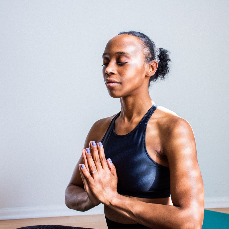 Peaceful woman in seated pose meditating with hands touching 