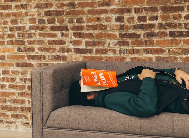 a man sleeping on a cough with a book on his face