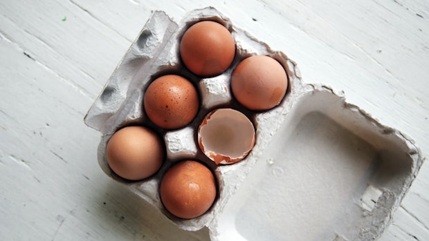 six eggs in a carton with one cracked egg