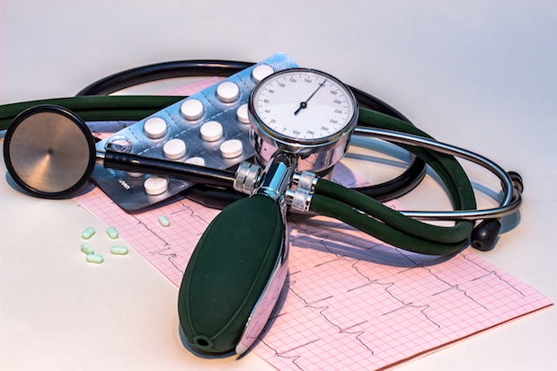 An image showing a stethoscope, EKG reading, medication and blood pressure gage