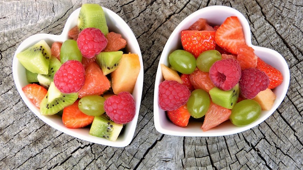 Two heart shaped bowls filled with a variety of fruit