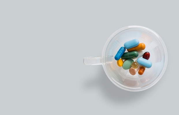 Different colored medications in a clear cup