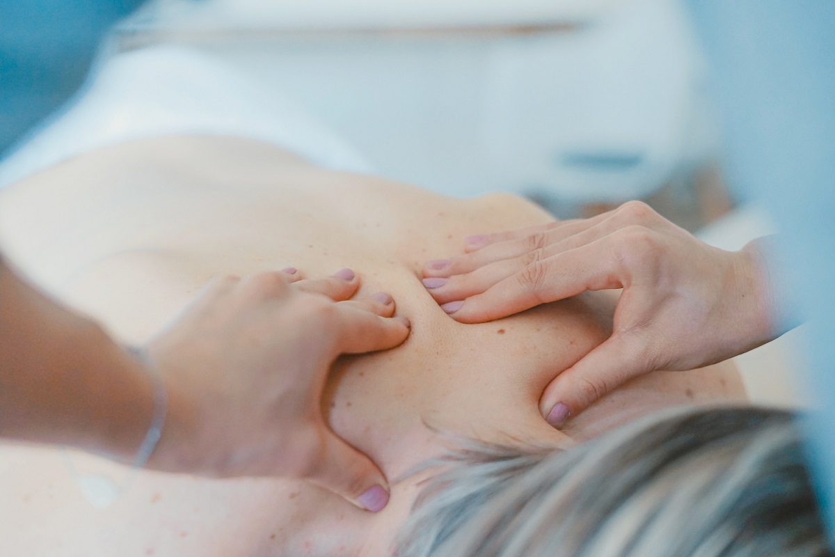 Bare back person receiving hands on massage on upper back